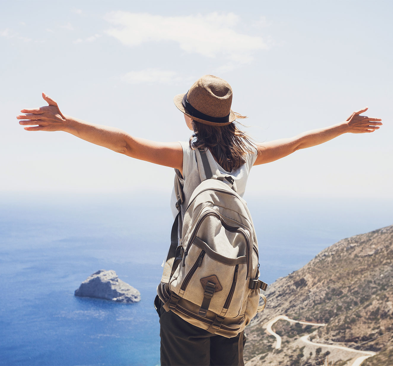 Woman who hiked with a backpack overlooking a scenic water view.