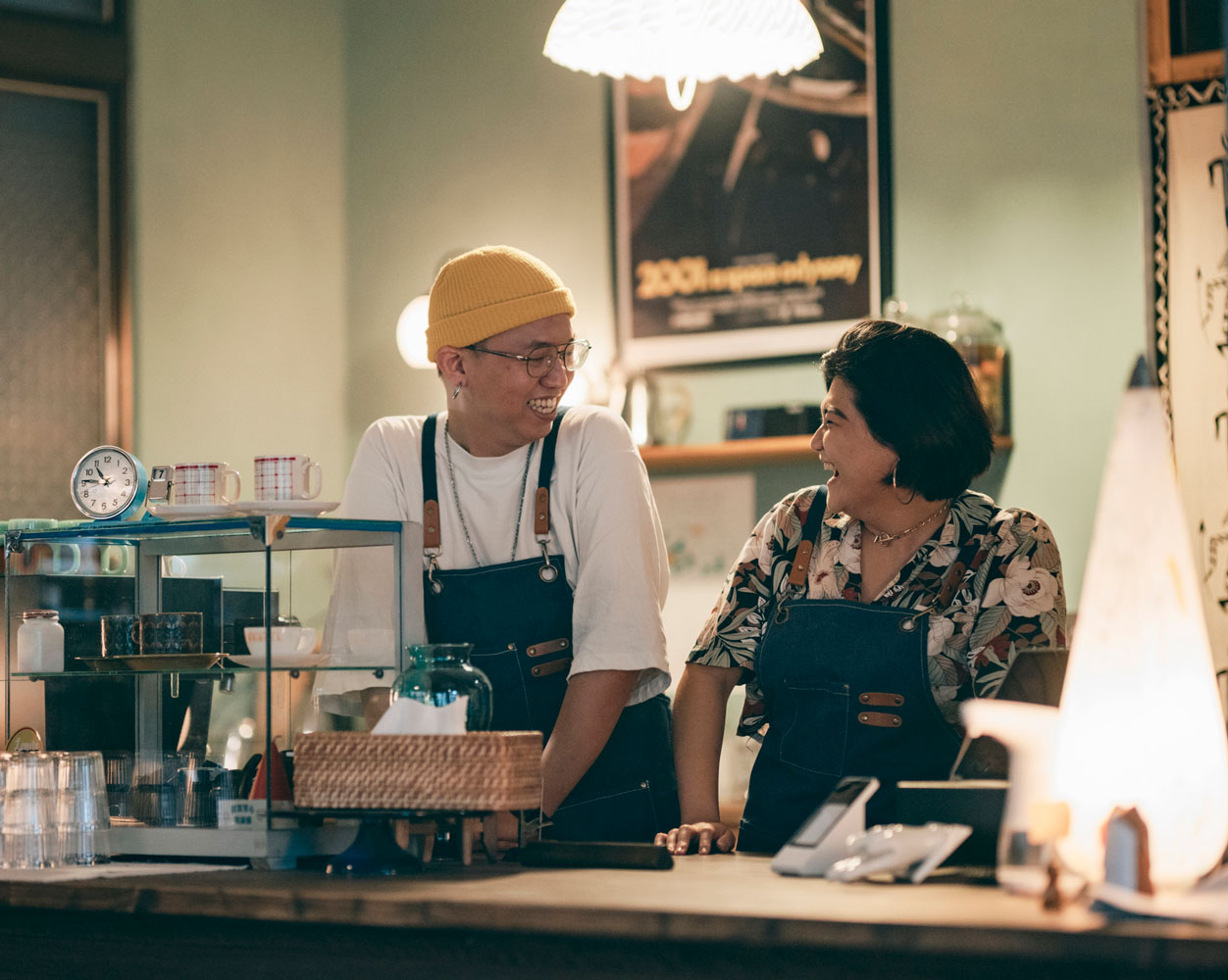 A coffee shop small business with two people laughing behind the counter.