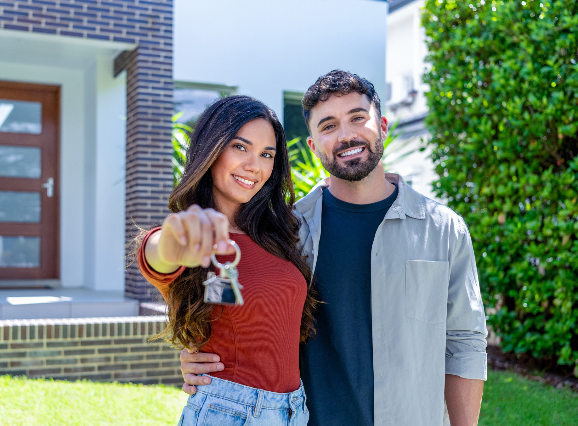 A couple hold out the keys to their newly purchased home.