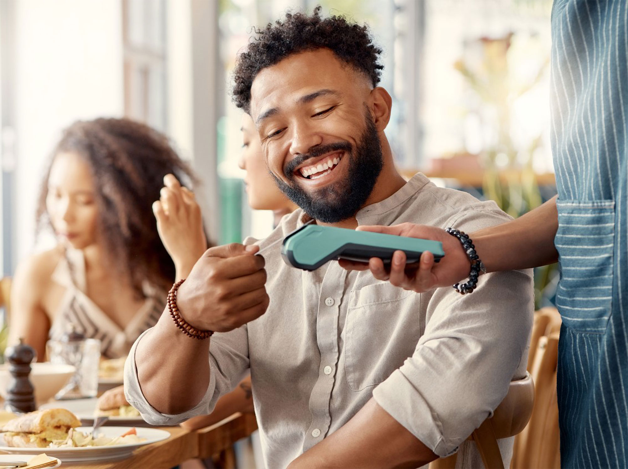 A man paying for a meal with friends with his Dover Federal Credit Union Mastercard credit card to help rebuild his credit.